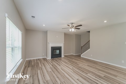 A spacious living room with wooden flooring and a fireplace.