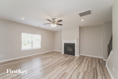 A spacious room with a fireplace and wooden flooring.