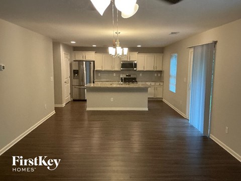 A spacious kitchen with wooden floors and a ceiling fan.