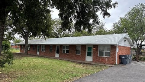 A small brick building with a green door and a green roof.