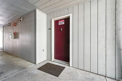 A red door is in a white building.