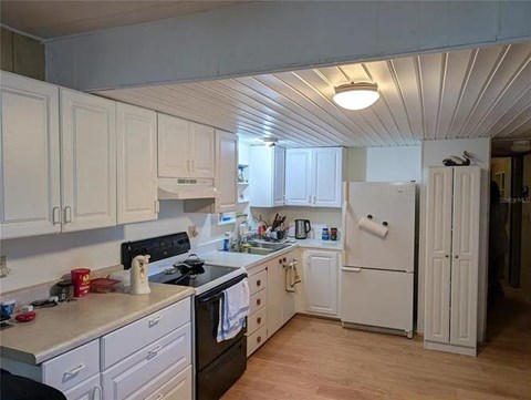 A kitchen with white cabinets and a white refrigerator.