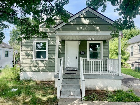 A small house with a porch and a white door.