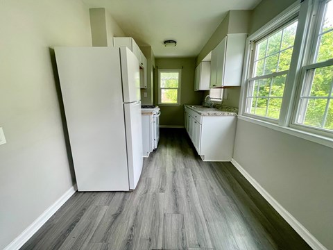 A kitchen with a white refrigerator and wooden floors.
