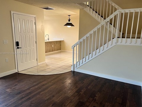 A white staircase with a wooden handrail and a white door.