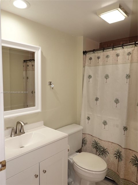 A white bathroom with a sink, toilet and shower curtain.