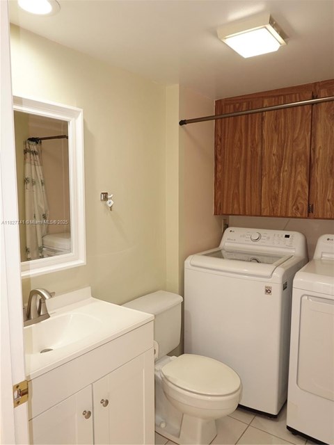 A white toilet sits next to a washer and dryer in a small bathroom.