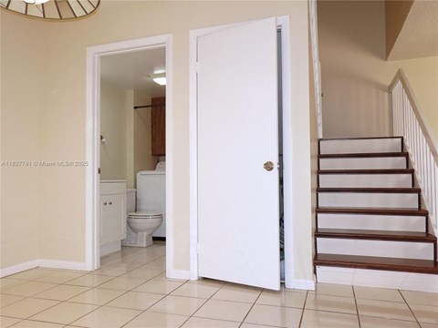 A white door is open to a bathroom with a toilet and sink.