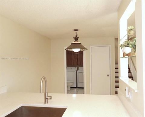 A kitchen with a sink and a light hanging from the ceiling.