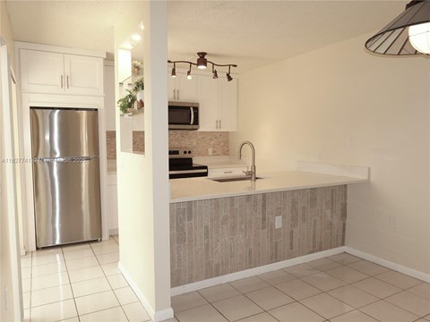 A kitchen with a stainless steel refrigerator and a countertop with a sink.
