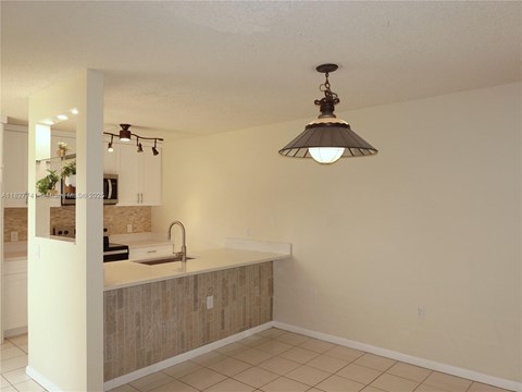 A kitchen with a sink and a hanging light fixture.