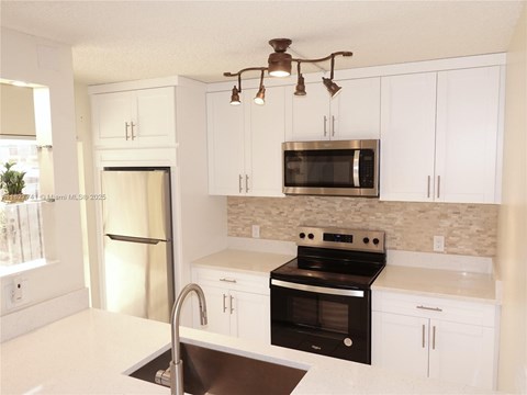 A kitchen with white cabinets and black appliances.