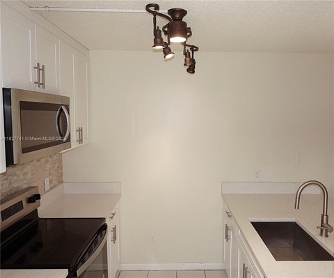 A kitchen with white cabinets and a black stove top oven.
