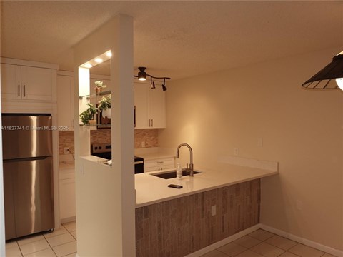 A kitchen with a stainless steel refrigerator and wooden cabinets.