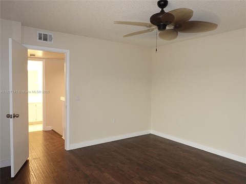 A room with a ceiling fan and a door leading to a hallway.