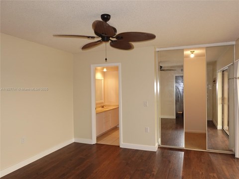 A room with a ceiling fan and a mirror on the wall.