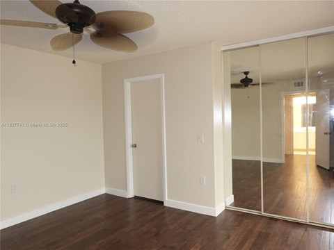 A room with a ceiling fan and a mirror on the wall.
