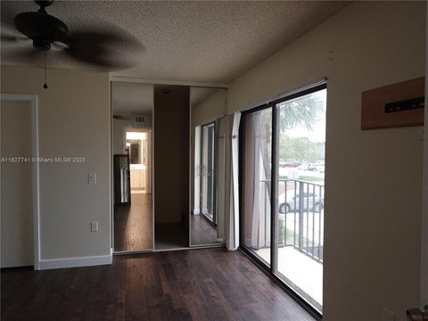 A living room with a ceiling fan and sliding glass doors.
