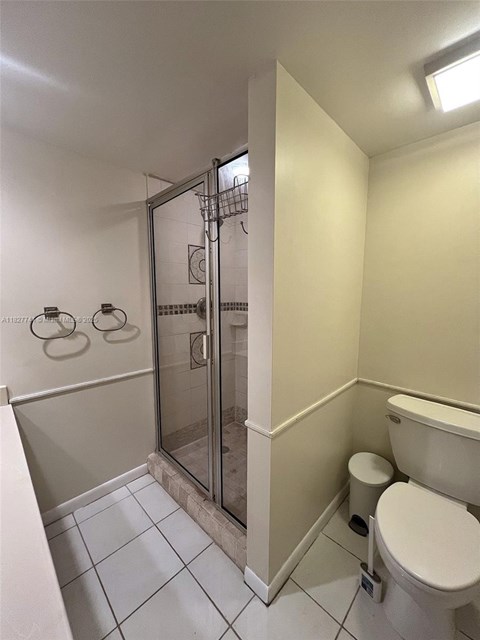 A white toilet sits next to a walk-in shower.