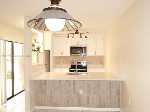A modern kitchen with a large island and a hanging light fixture.