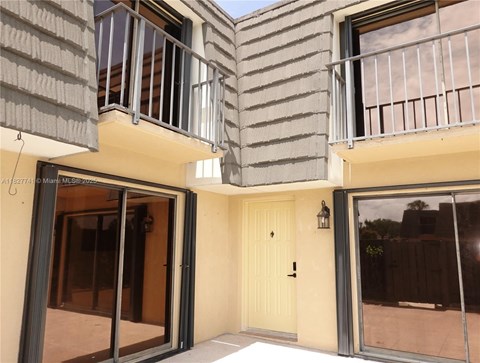 A balcony with a white door and a glass door leading to a patio.