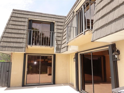 A modern house with a balcony and a black gate.