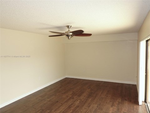 A room with a ceiling fan and wooden flooring.