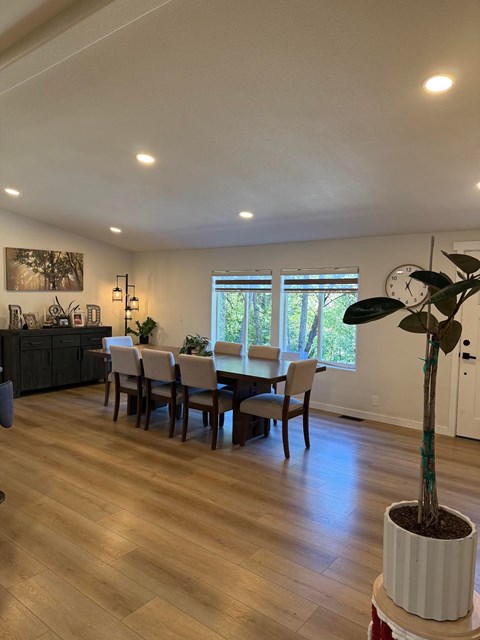 A dining room with a table set for four and a potted plant on a table.