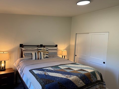 A bed with a white comforter and a quilt on it.