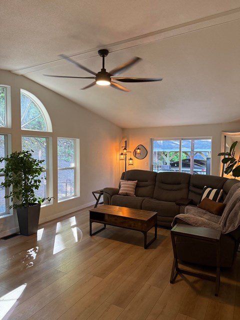A living room with a ceiling fan and a large window.