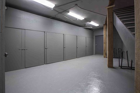 A long hallway with grey doors and a concrete floor.