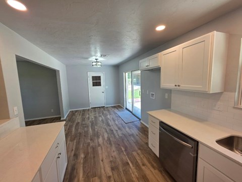 A kitchen with white cabinets and a wooden floor.