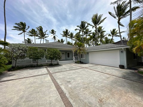 A house with a driveway and palm trees in the background.