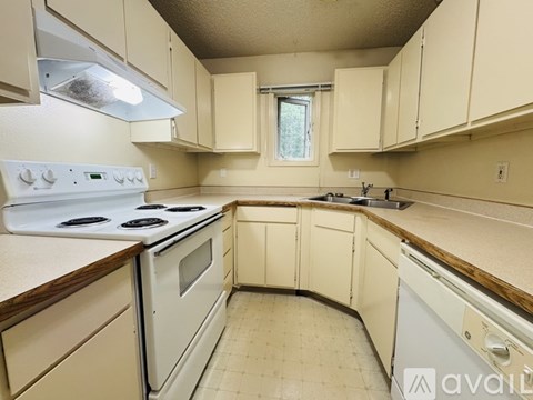 A kitchen with white appliances and beige cabinets.