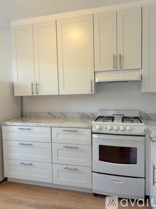 A kitchen with white cabinets and a white gas stove.