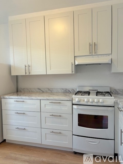A kitchen with white cabinets and a white gas stove.