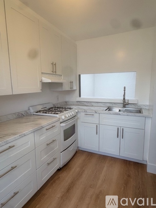 A kitchen with white cabinets and a wooden floor.