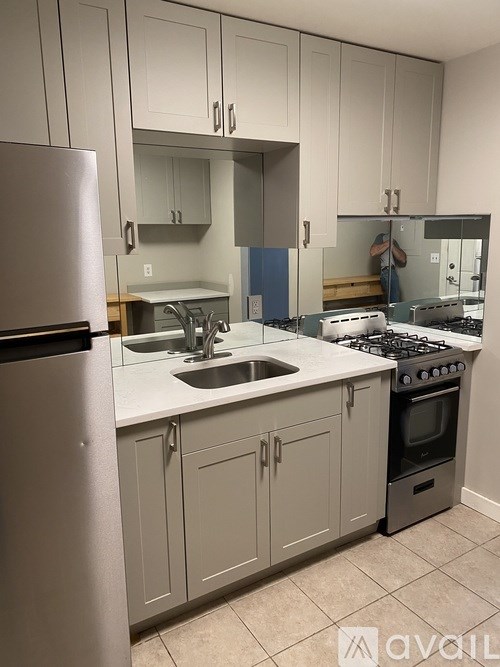 A kitchen with a stove, sink, and cabinets.