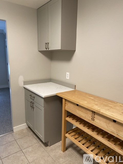 A kitchen with a wooden table and grey cabinets.