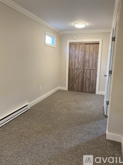 A room with a carpeted floor and a wooden door.