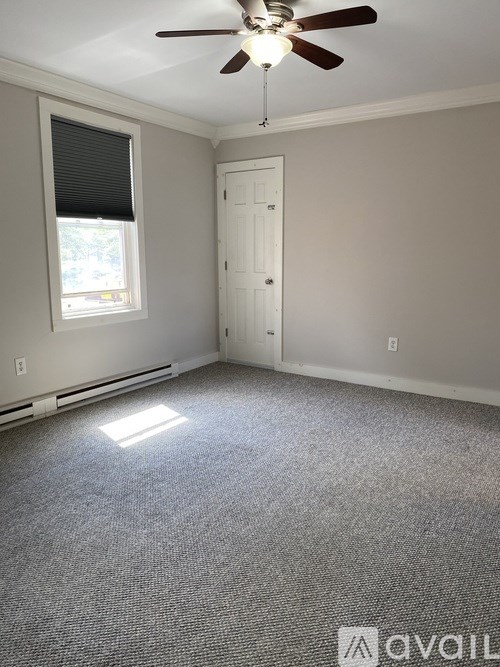 A room with a ceiling fan and a door.