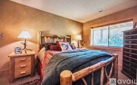 A bedroom with a bed, nightstand, and window.
