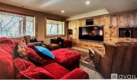 A living room with a red couch and a wooden wall.