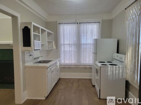 A kitchen with white appliances and cabinets is available for rent.