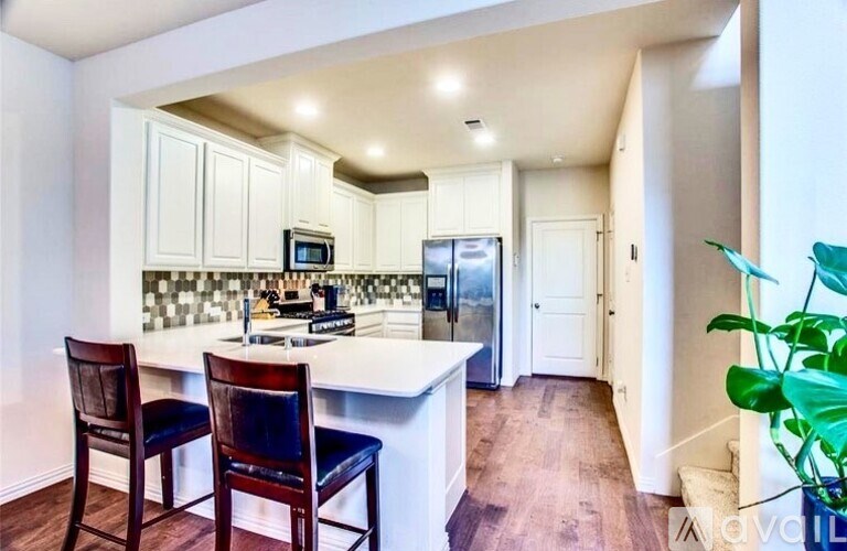 A kitchen with white cabinets and a wooden floor.