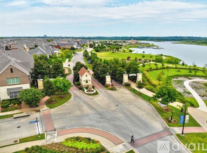 A residential area with a road leading to a white building with a statue in front.
