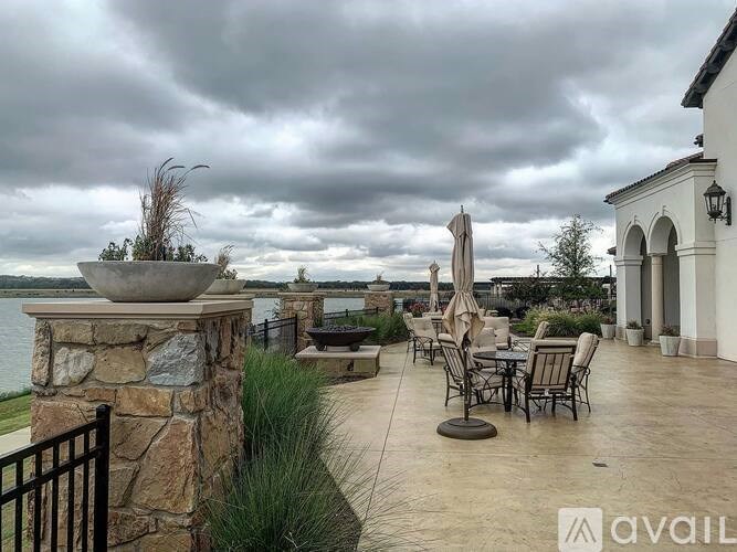 A patio with a table and chairs overlooking a body of water.
