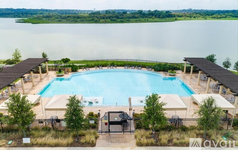 A large outdoor swimming pool surrounded by a fence and trees.