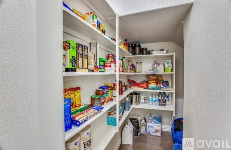 A pantry with white shelves filled with food and drinks.
