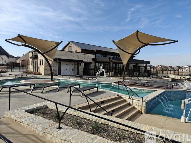 A pool area with a sun shade and steps leading down to a pool.